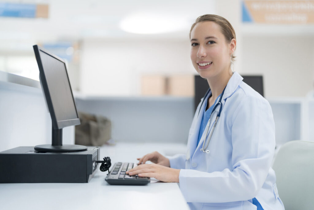 A female doctor, specializing in healthcare business consulting, sitting in front of a computer. - Payor Contract Negotiations - Complete Healthcare Business Consulting